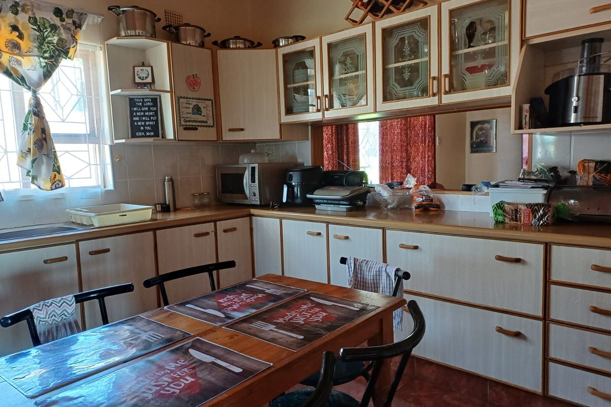 A functional kitchen featuring laminate cabinetry, tiled backsplash, and a mirror splashback, providing ample storage and workspace for daily meal preparation.