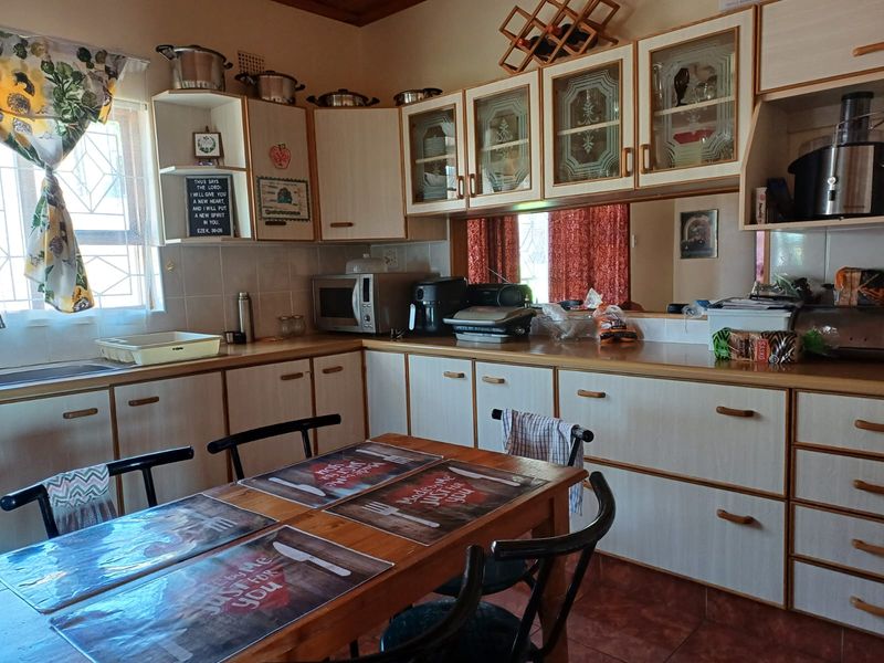 A functional kitchen featuring laminate cabinetry, tiled backsplash, and a mirror splashback, providing ample storage and workspace for daily meal preparation.