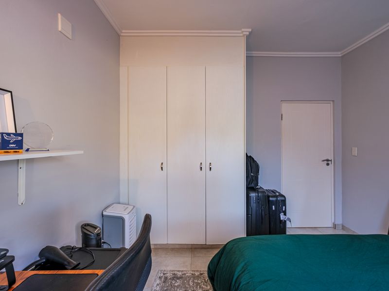 A bedroom featuring neutral walls, tiled flooring, decorative coving, and a white built-in wardrobe.