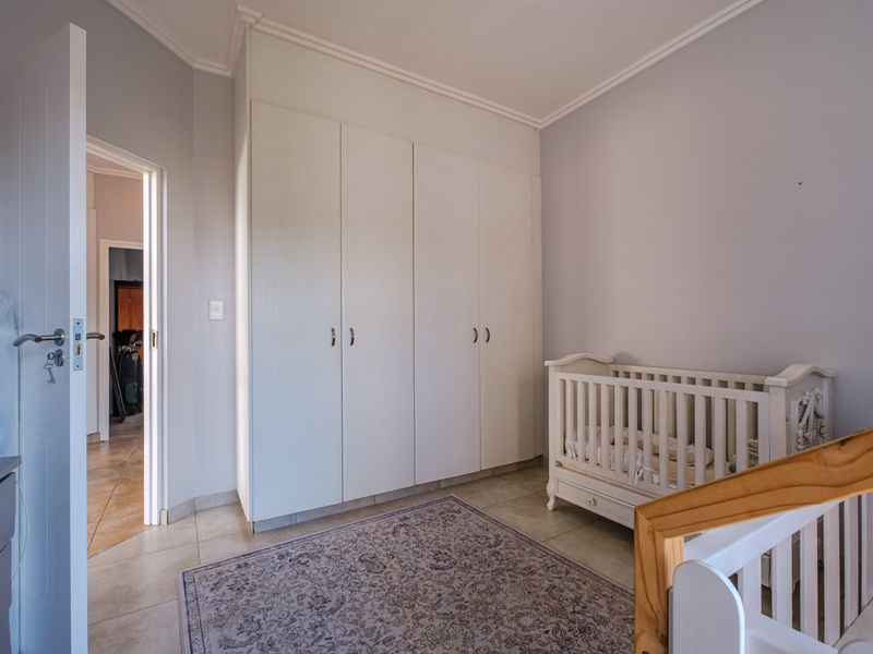 A bedroom featuring neutral wall tones, tiled flooring, and ample built-in cupboard storage space.