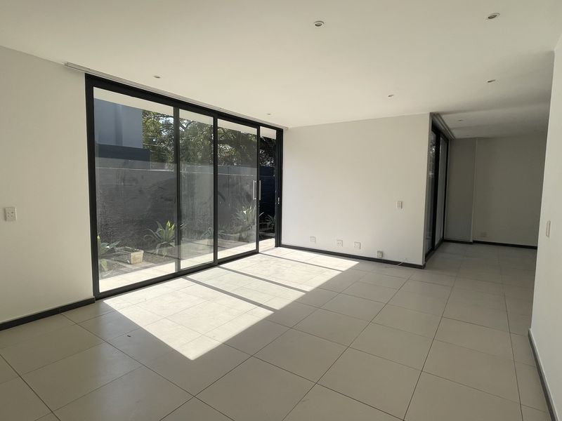 A bright, open-plan living area featuring large sliding glass doors that provide ample natural light and direct access to the outdoor space.