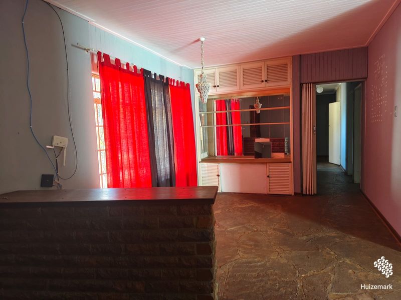 A dated bar area featuring a brick-faced counter, built-in cabinetry, stone flooring, and timber ceiling, offering potential for a modern entertainment space renovation.