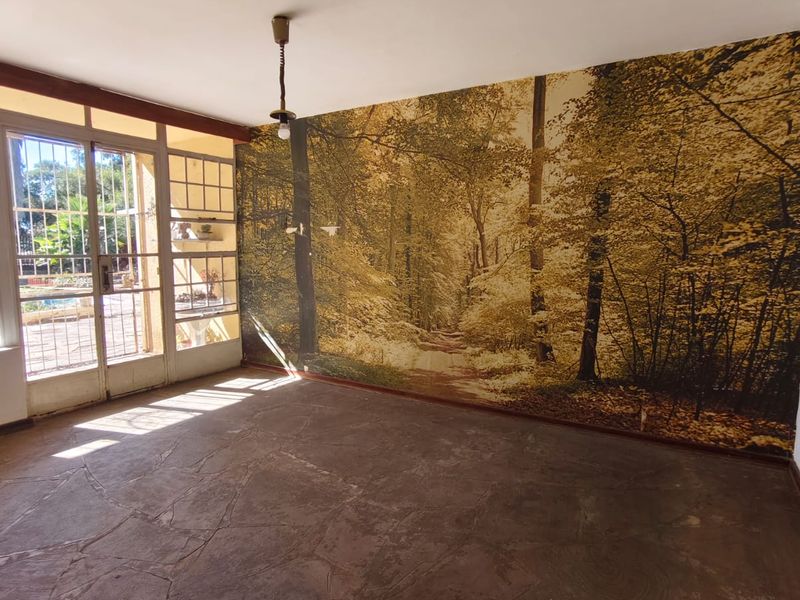 An empty living room featuring natural flagstone flooring, a large forest-themed mural wall, and glass-paned french doors leading to the exterior.