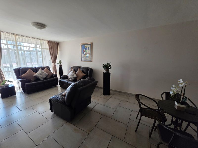 Spacious open-plan living and dining area featuring large windows, tiled flooring, and neutral wall finishes, offering a bright and versatile living space.