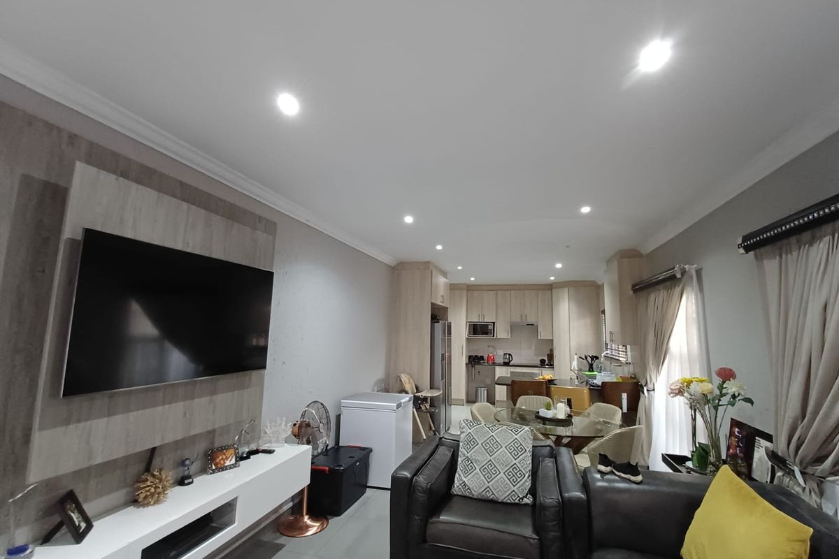 Spacious open-plan living and dining area featuring modern kitchen cabinetry, tiled floors, recessed lighting, and a built-in media unit.