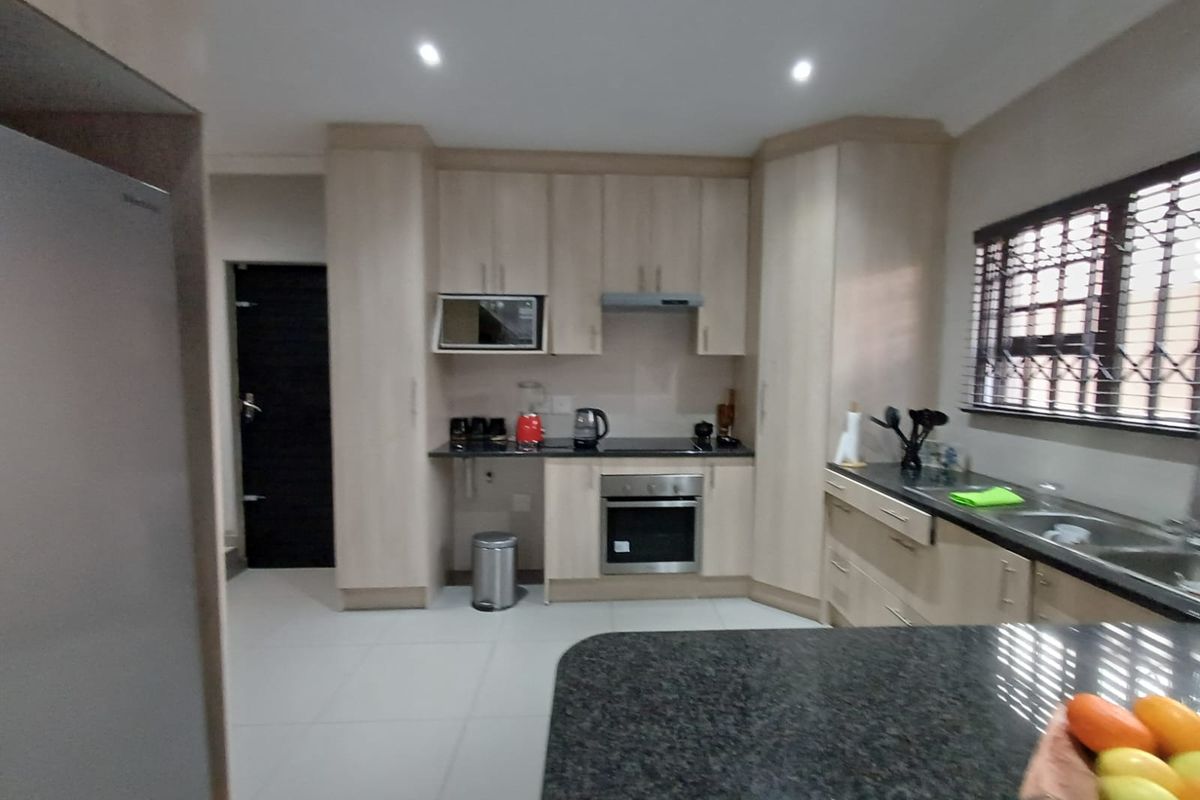Modern kitchen featuring light wood cabinetry, granite countertops, built-in oven and hob, and tiled flooring with a functional layout.