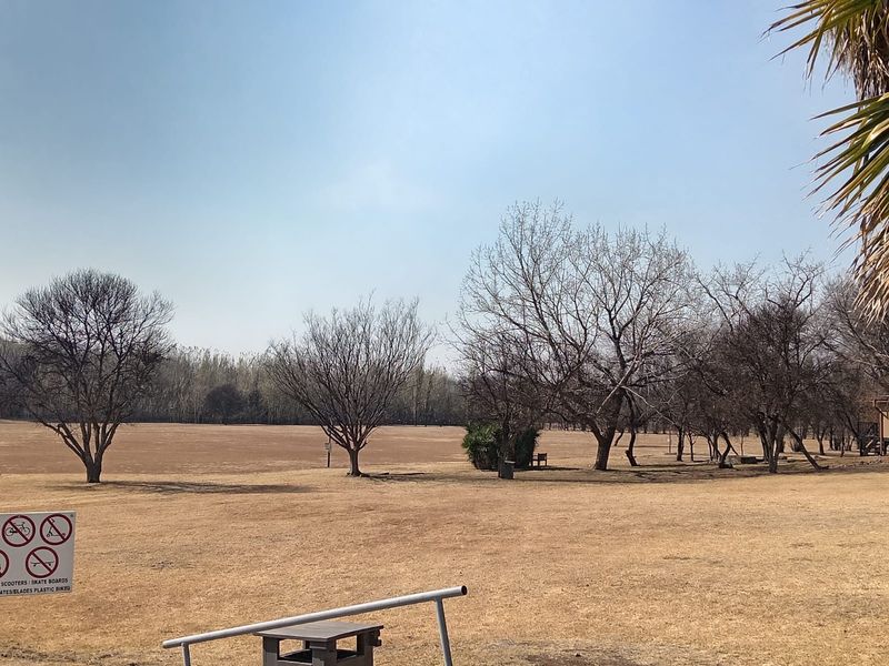A view of a large, open garden area featuring mature trees and expansive grass grounds.