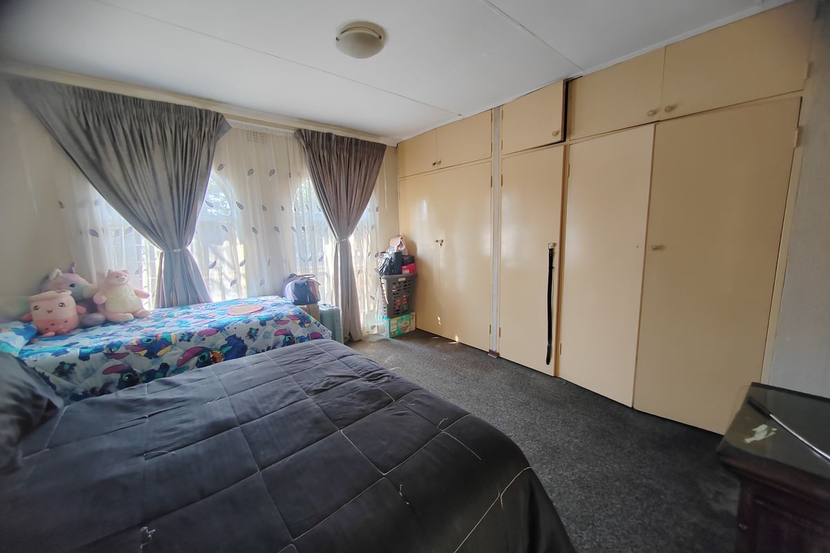 A bedroom featuring extensive built-in cupboards with overhead storage and carpeted flooring.