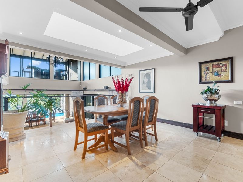 Spacious dining area featuring stone tile flooring, a large skylight, and clerestory windows overlooking the lower level and pool area.