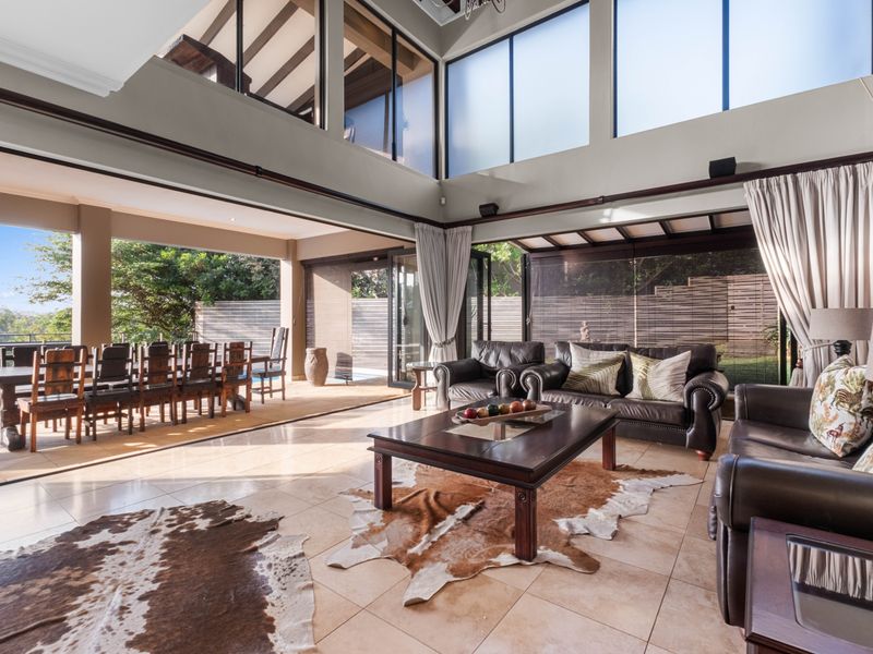 Spacious open-plan living and dining area featuring vaulted ceilings, clerestory windows, and seamless indoor-outdoor flow through large sliding glass doors.