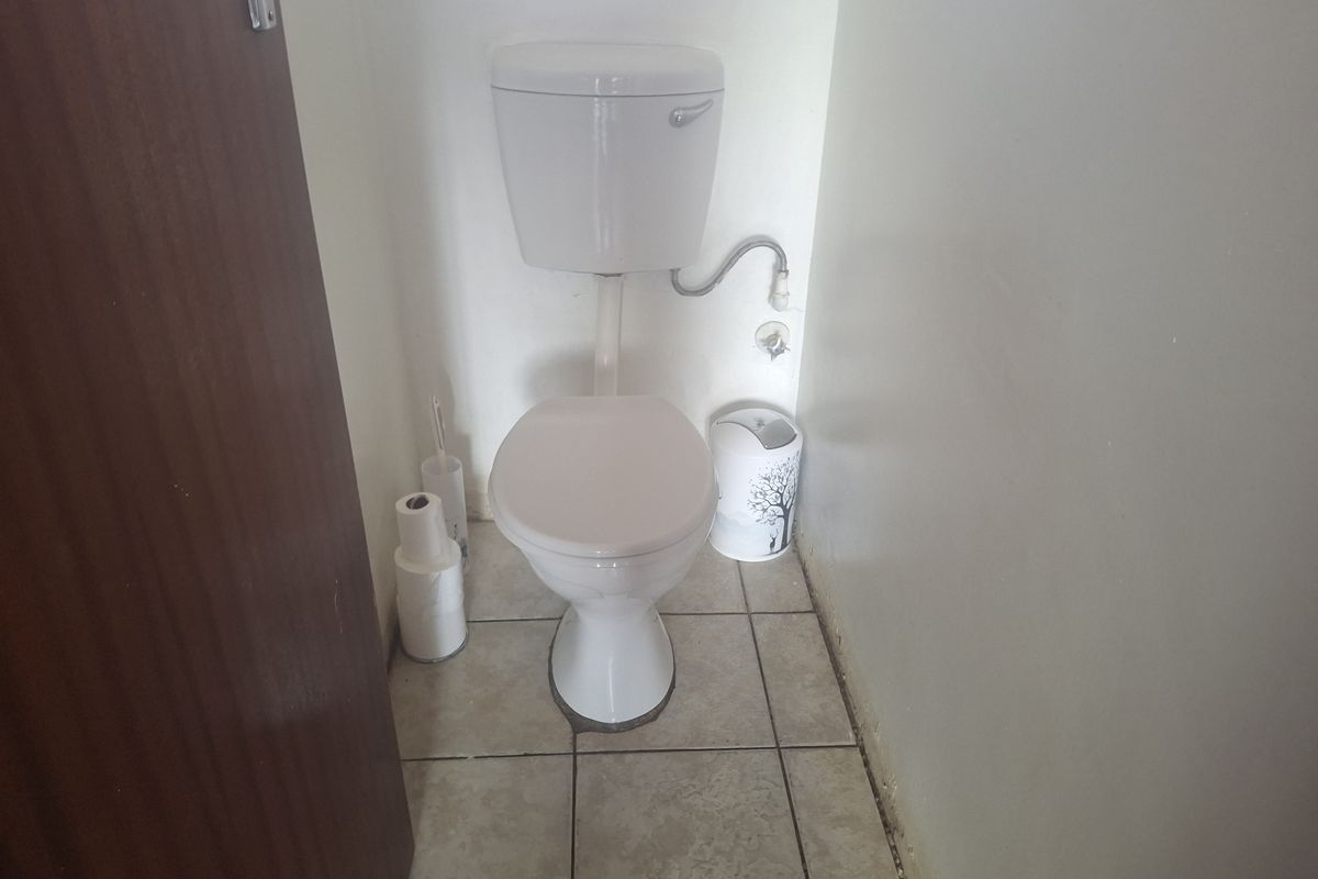 A small bathroom featuring a standard toilet and ceramic floor tiling, requiring minor maintenance and cosmetic updates.