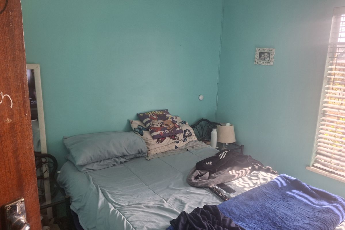 A bedroom featuring teal painted walls and venetian blinds, requiring cosmetic updates to improve the overall aesthetic and condition of the space.