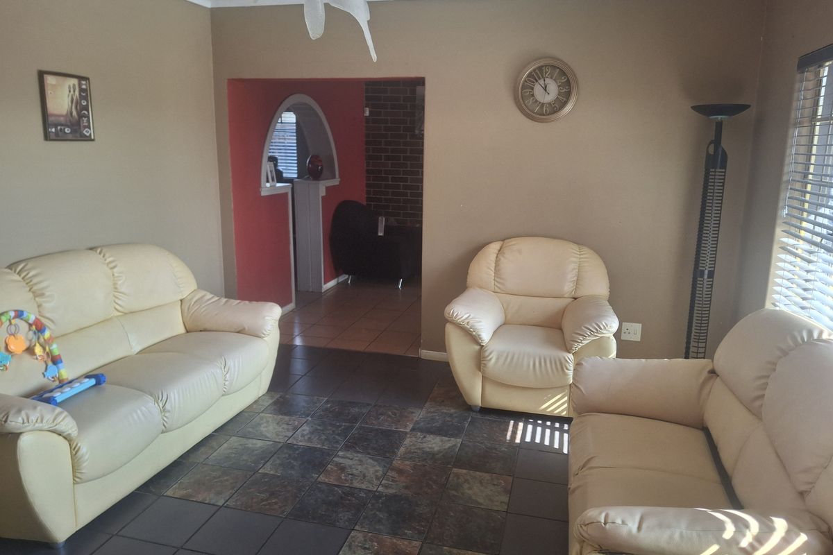A living room featuring dark tiled flooring, an arched entryway, and a brick feature wall, providing a functional and connected living space.