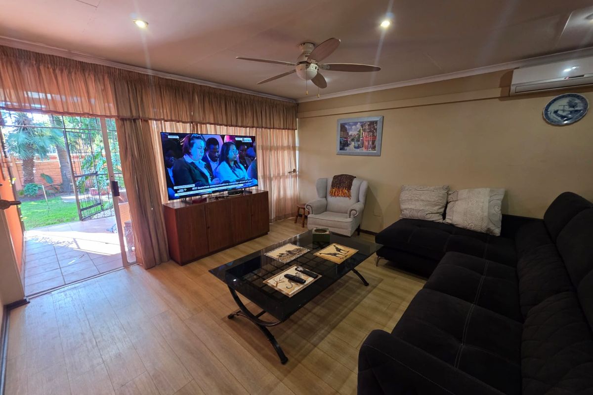 A comfortable living room featuring laminate flooring, a ceiling fan, and a sliding glass door providing direct access to the outdoor patio area.