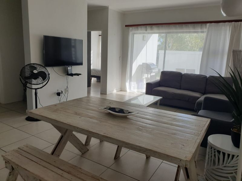 Open-plan living and dining area featuring tiled flooring and large sliding glass doors providing natural light and access to the outdoor space.