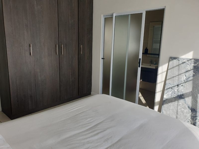 Bedroom featuring dark wood built-in wardrobes and a sliding glass door providing access to an en-suite bathroom.