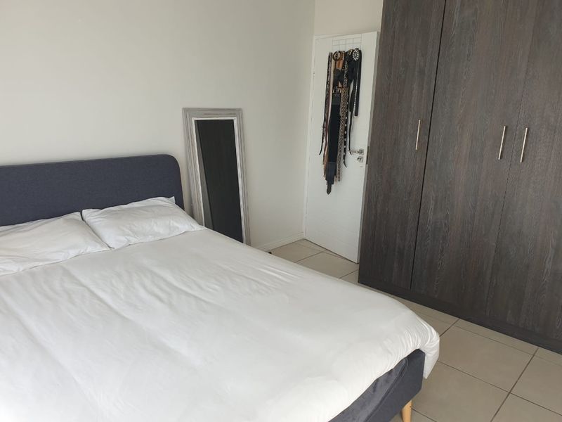 A bedroom featuring tiled flooring and a dark wood built-in wardrobe.