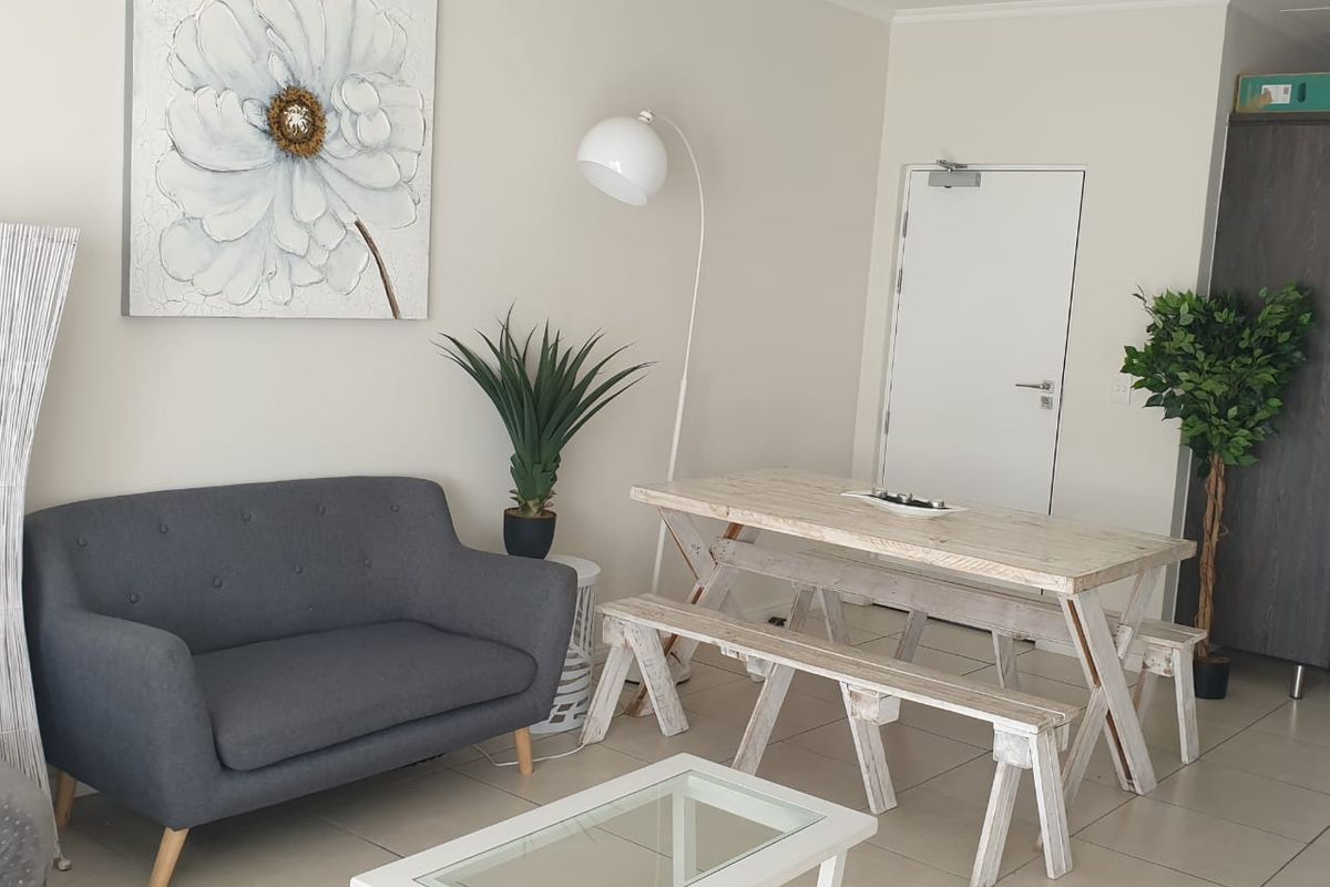 A bright living area featuring neutral tiled flooring and a built-in storage cupboard, offering a clean and functional space.