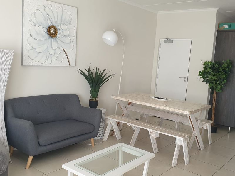 A bright living area featuring neutral tiled flooring and a built-in storage cupboard, offering a clean and functional space.