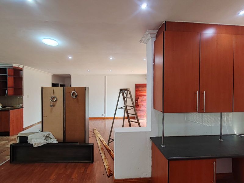 Open plan living area featuring laminate flooring, recessed lighting, and built-in cabinetry, currently undergoing renovation with visible unfinished elements.