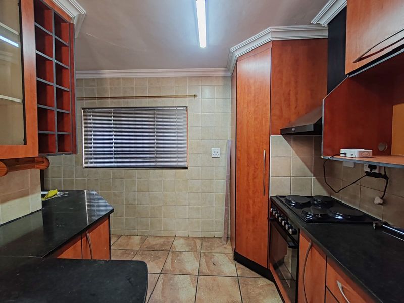 A functional kitchen featuring wooden cabinetry, granite countertops, and built-in cooking appliances, offering a solid foundation for a modern renovation.