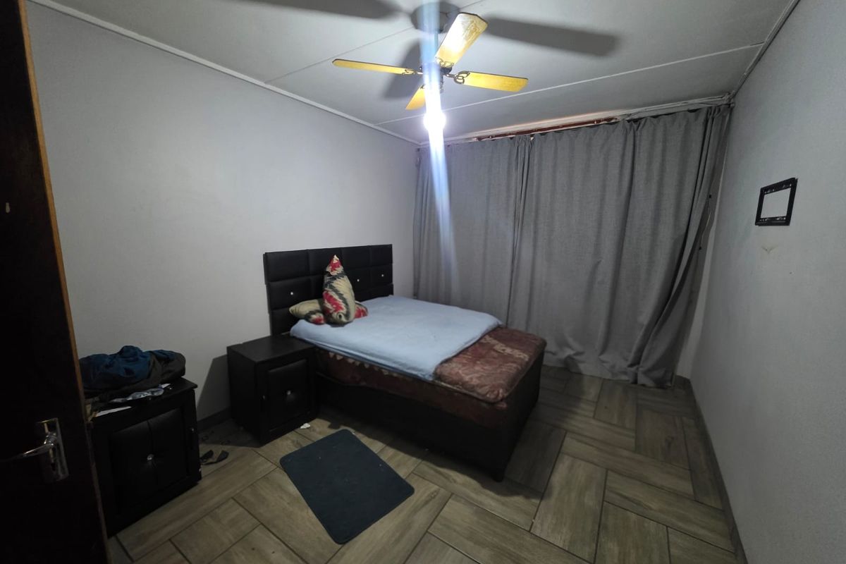 A bedroom featuring tiled flooring and a ceiling fan, providing a functional space for rest.