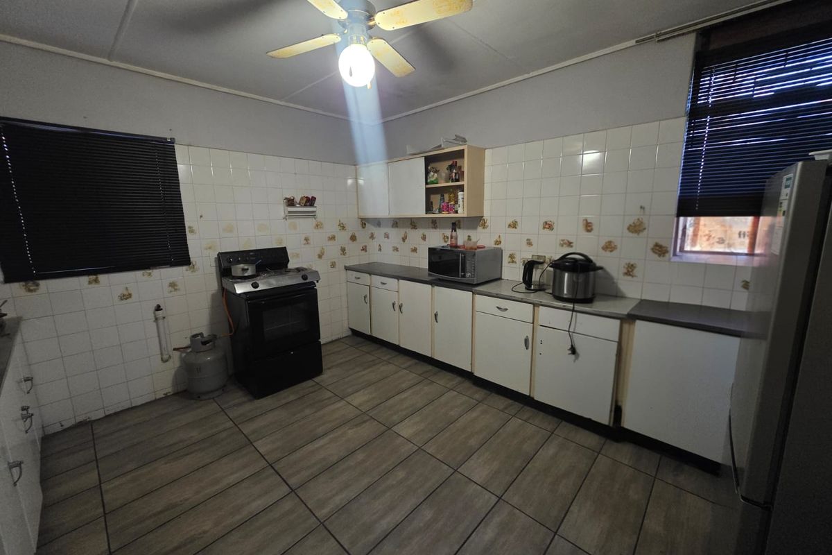 A functional kitchen featuring tiled flooring, a gas stove, and ample built-in cabinetry with a tiled splashback.