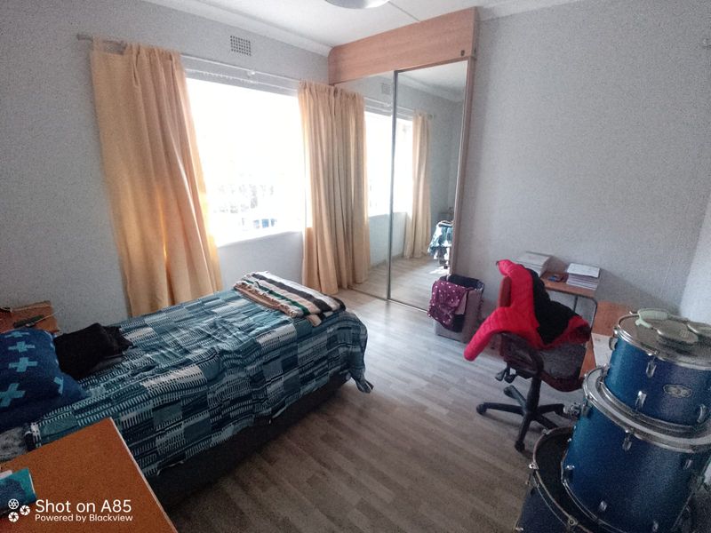 A bedroom featuring laminate flooring and a built-in wardrobe with mirrored sliding doors, providing ample storage space.