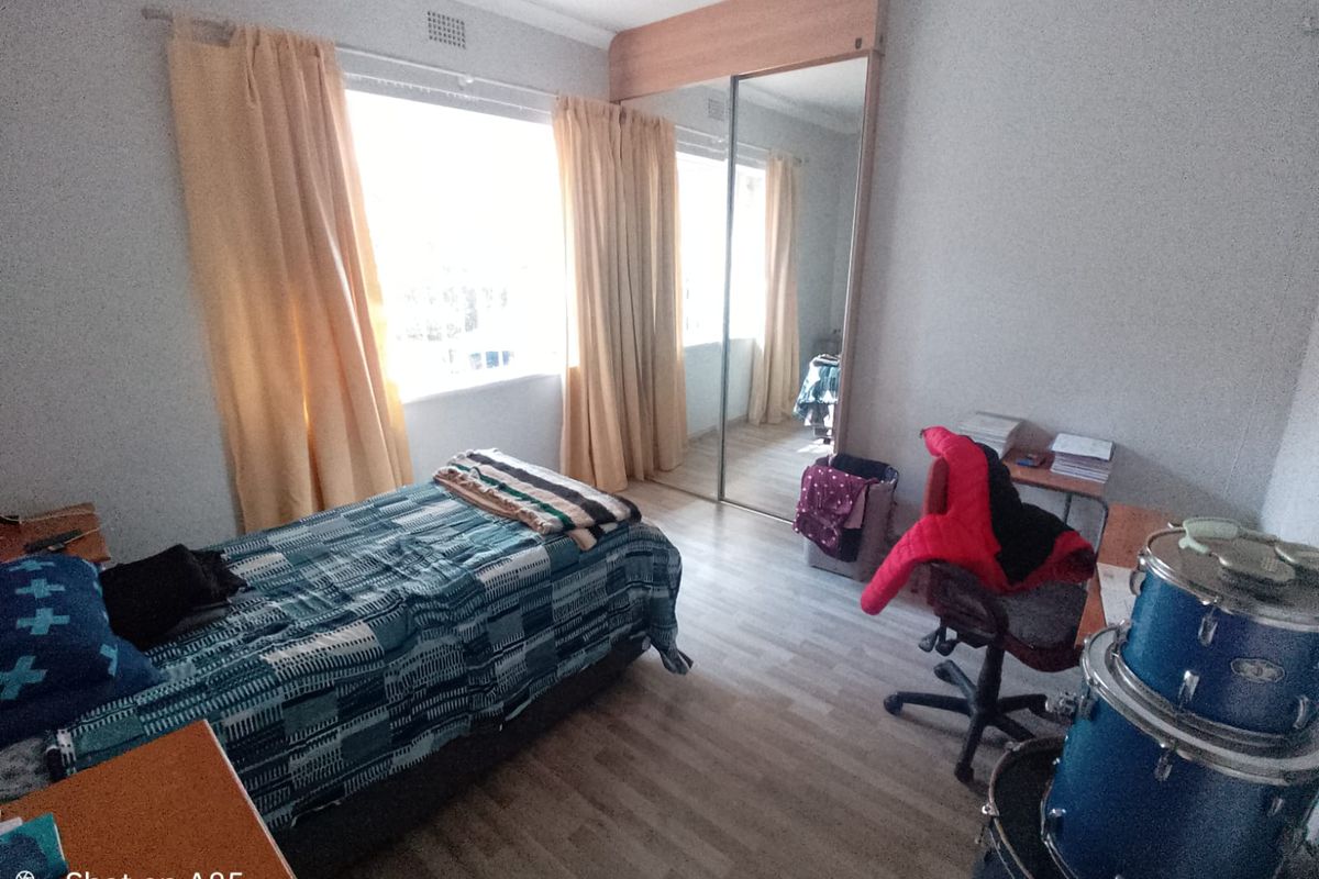 A bedroom featuring laminate flooring and a built-in wardrobe with mirrored sliding doors, providing ample storage space.