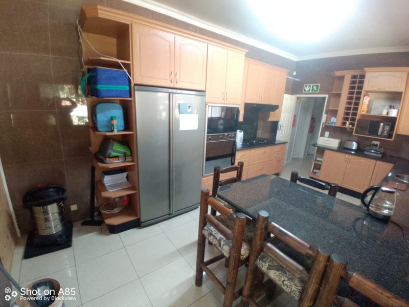 A functional kitchen featuring light wood cabinetry, granite countertops, built-in oven, and extractor fan, with tiled flooring throughout.