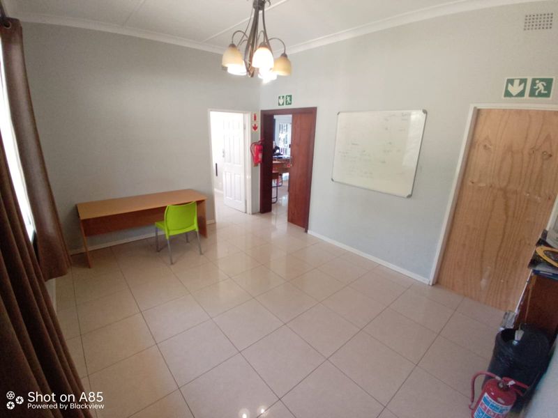A functional office space featuring tiled flooring, neutral walls, and standard interior doors, suitable for a professional workspace or study area.