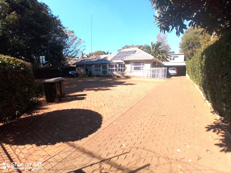 Front view of a residential property featuring a large paved driveway, tiled roof, and installed solar panels.