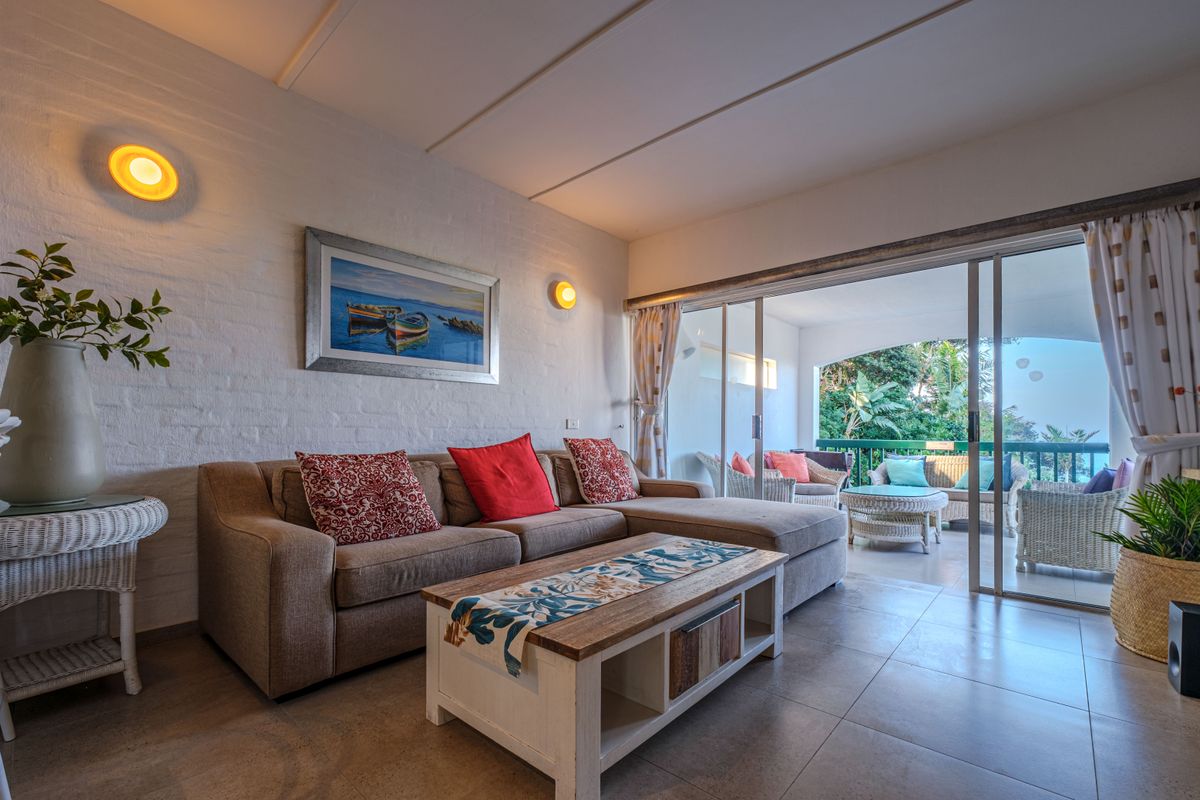 A comfortable living room featuring tiled floors, exposed brick walls, and large sliding glass doors that open onto a covered patio.