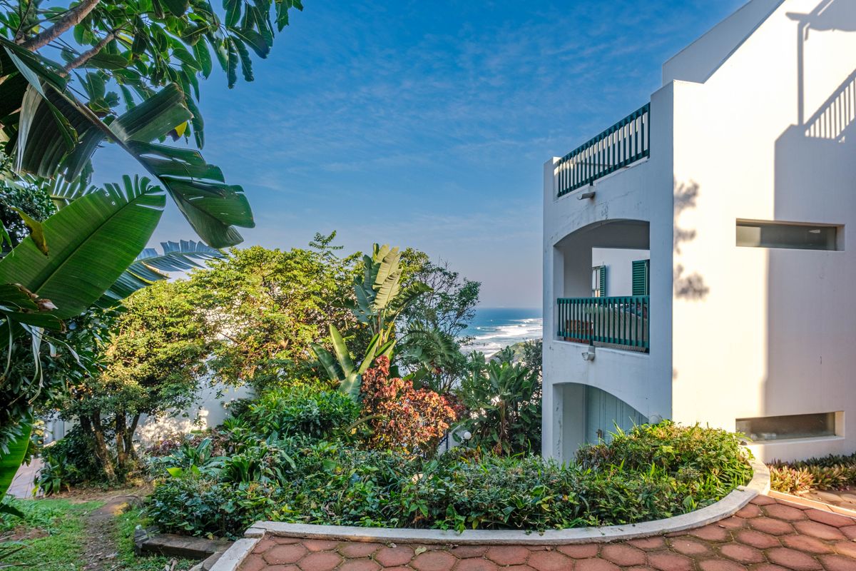 Rear view of the townhouse featuring multi-level balconies, lush garden landscaping, and scenic ocean views.