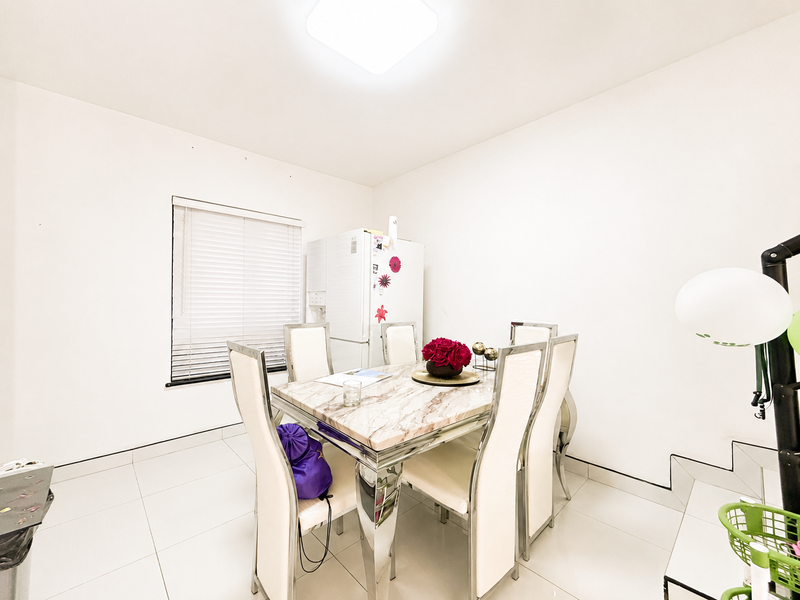 A bright dining area featuring tiled flooring, a window with venetian blinds, and a central ceiling light fixture.