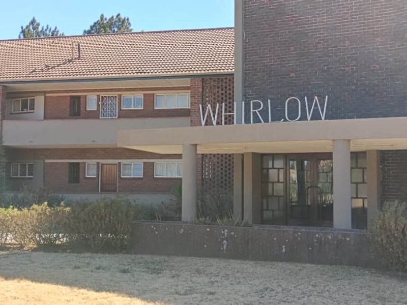 Front elevation of the Whirlow apartment complex featuring a brick facade, covered entrance canopy, and established garden landscaping.