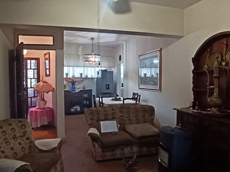 An open-plan living and dining area featuring a connecting archway and traditional layout, offering potential for modernization and improved flow.