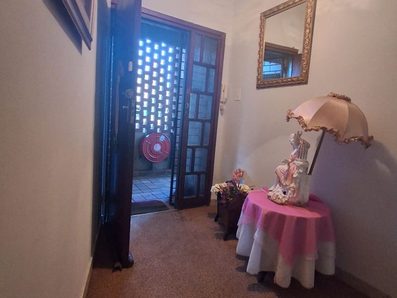 A functional entrance hallway featuring a timber door leading to an outdoor balcony area with a fire hose reel visible.