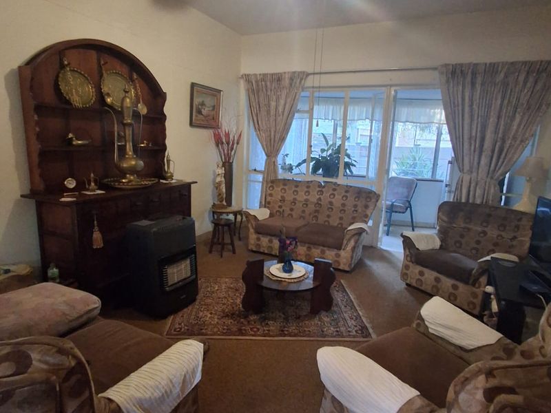 A living room featuring carpet flooring, a ceiling fan, and a sliding glass door providing access to an outdoor area.