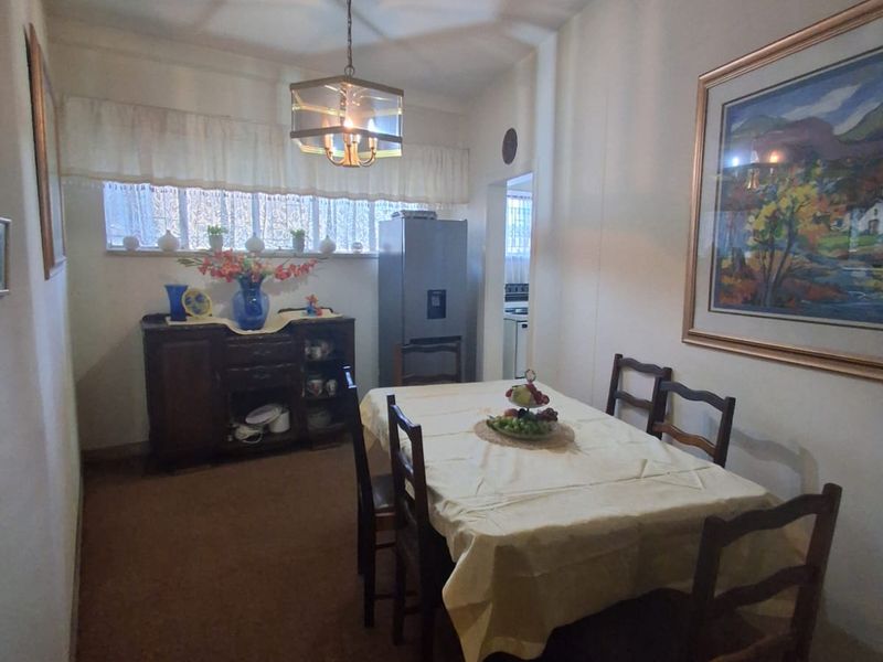 A dining room featuring a central pendant light fixture and a window with a valance, providing a functional space for meals.