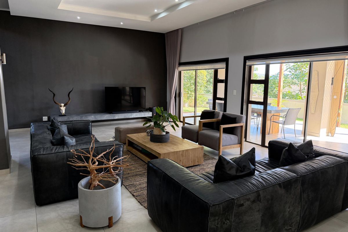 Spacious modern living room featuring a floating concrete media console, recessed ceiling with downlights, and large sliding glass doors leading to an outdoor patio.