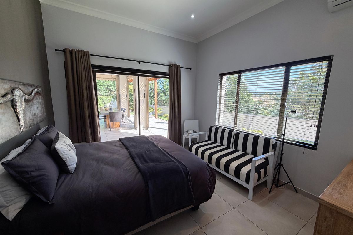 Spacious bedroom featuring tiled floors, recessed lighting, air conditioning, and large sliding doors providing direct access to an outdoor patio area.