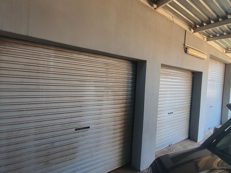 A triple garage featuring metal roller shutter doors and a corrugated roof structure.