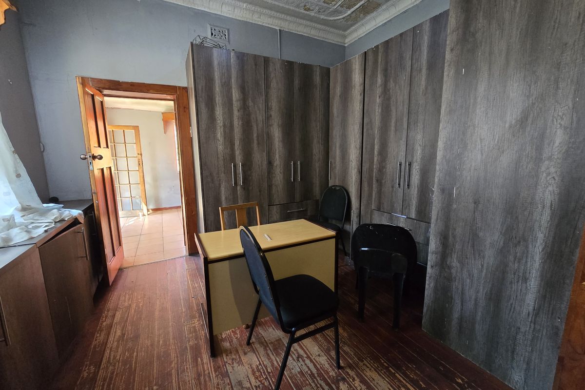Bedroom featuring built-in cupboards, ornate ceiling detail, and original timber flooring, requiring cosmetic updates to restore its character.