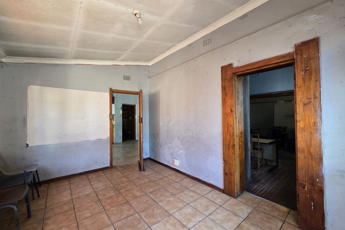 An empty living area featuring tiled flooring and timber door frames, requiring cosmetic updates to the walls and ceiling.