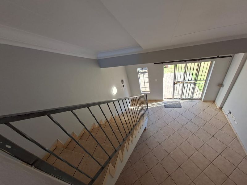 Entrance area featuring a tiled staircase with a metal balustrade, leading to a secure exterior door with a metal security gate.