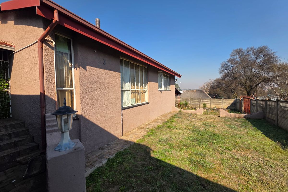 Rear exterior view of the house featuring a paved walkway, lawn area, and precast concrete boundary wall.