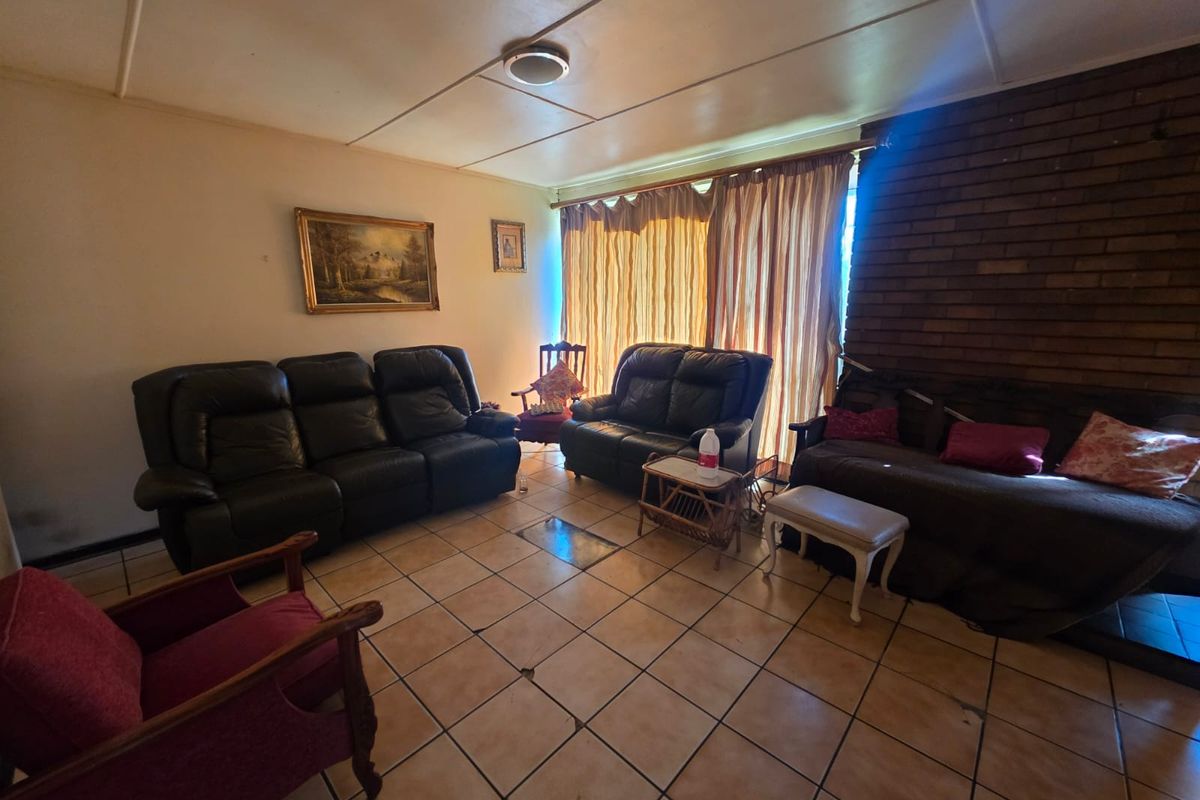 A living room featuring a brick fireplace and ceramic tile flooring, offering a traditional layout with potential for modernization.