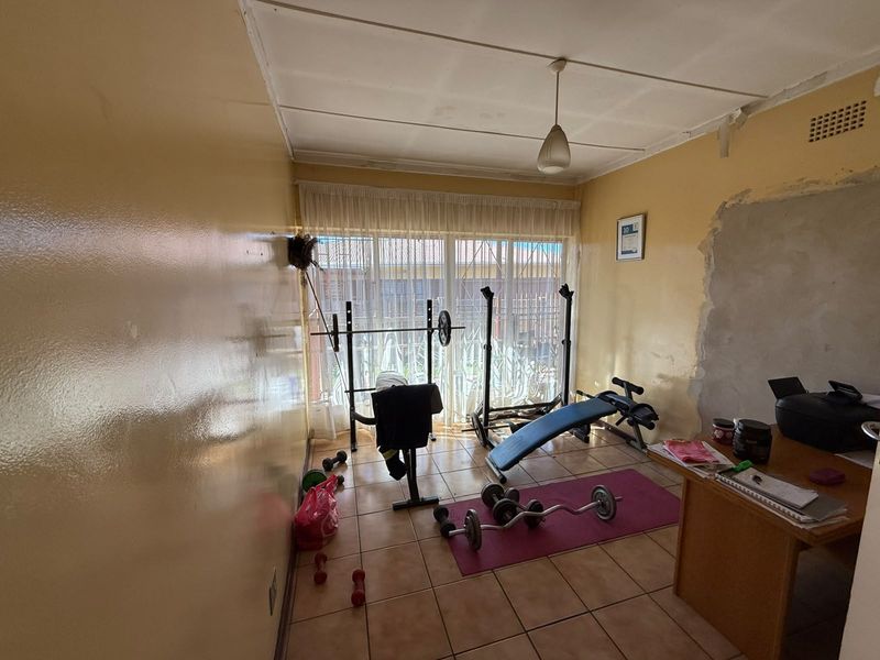 A bedroom space featuring tiled flooring and a sliding glass door, currently requiring wall and ceiling repairs to restore its condition.