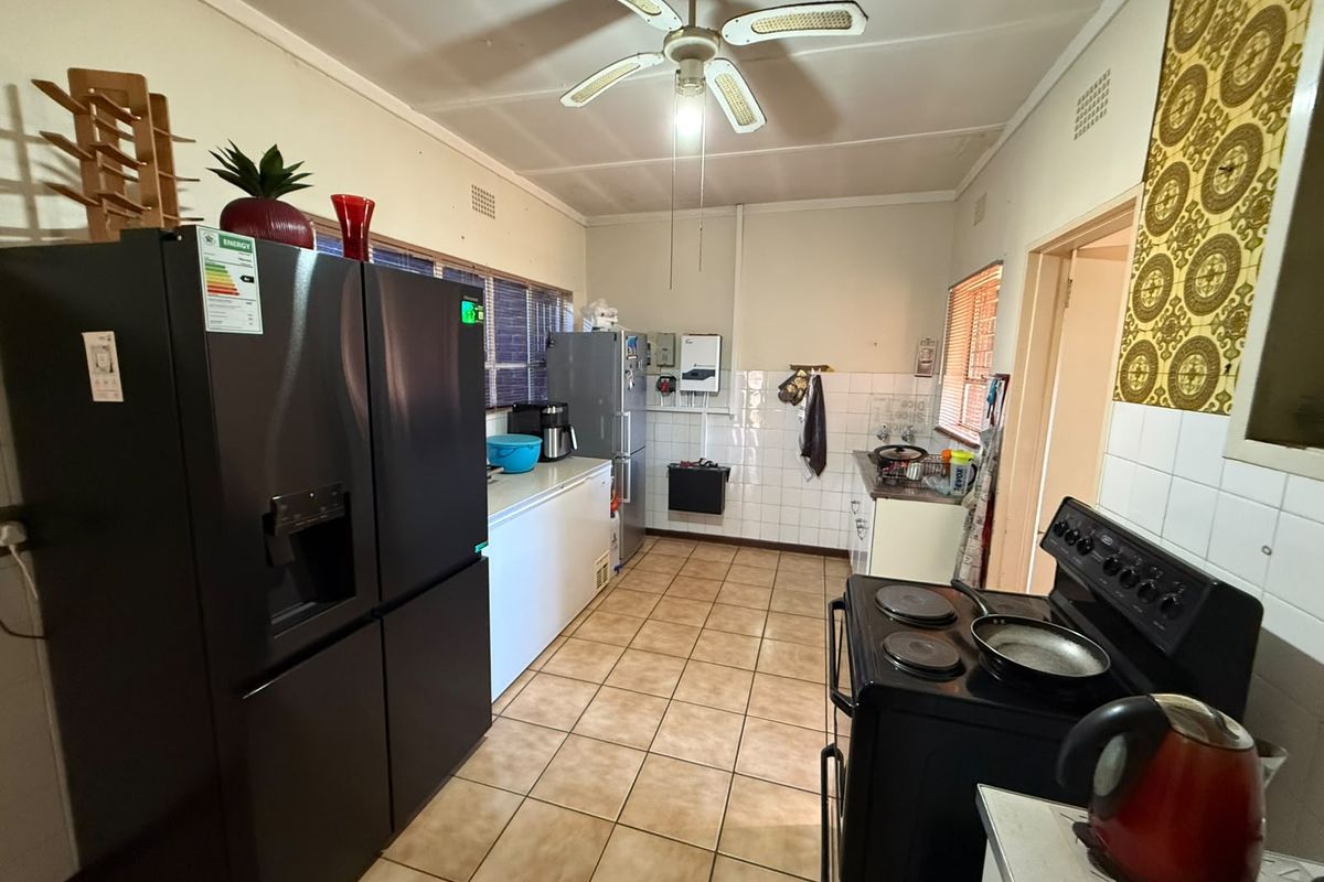 A functional kitchen featuring tiled flooring, a ceiling fan, and a tiled splashback, offering a practical layout with ample space for appliances.
